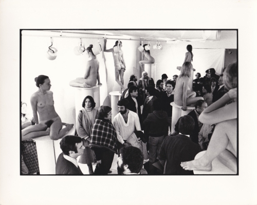 Installation view of 1976 show Women in Glasses: audience meandering around nude women on pedestals with eye glasses.